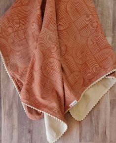 an orange and white blanket sitting on top of a wooden floor