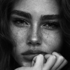 a black and white photo of a woman with freckles on her face looking at the camera