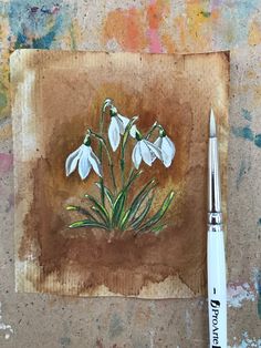 a painting with some flowers on it next to a paintbrush and watercolor paper