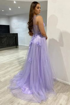 a woman in a purple dress standing next to a wall and looking at the floor