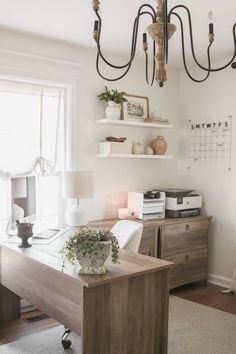 a room with a desk, shelves and a chandelier hanging from the ceiling