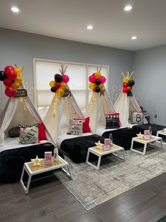 a room decorated with teepee tents and balloons