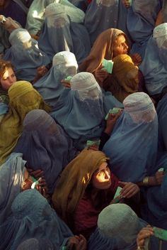 a group of women in blue veils are brushing their teeth with green toothbrushes