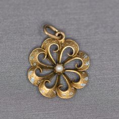 "Sweet Victorian Enamel and Pearl Flower Style Pendant Charm in 14k Yellow Gold This sweet old pendant harkens to times long ago.  The piece features a scalloped floral design and the remnants of turquoise blue enamel.  The pearl center grounds the piece.  We think this makes a lovely pendant or charm.  The piece measures 1\" in height including the bail and is 3/4\" across in width.  The piece is crafted in 14k and weighs 1.60g." Yellow Gold Enamel Jewelry With Flower Charm, Antique Gold Flower Jewelry, Yellow Gold Enamel Flower Pendant Jewelry, Gold Enamel Art Nouveau Jewelry, Art Nouveau Gold Enamel Jewelry, Vintage Jewelry With Flower Charm And Pendant, Vintage Flower Charm Pendant Jewelry, Vintage Medallion Jewelry With Flower Charm, Heirloom Yellow Gold Flower-shaped Jewelry