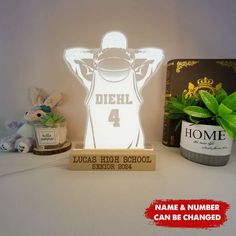 personalized lamp with name and number displayed on shelf next to potted green plant