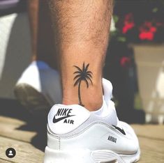 a man's foot with a palm tree tattoo on his left side and the word air written in black ink