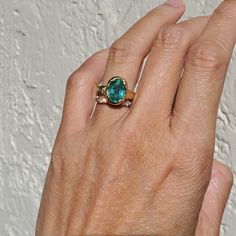 a woman's hand with a ring on it that has a blue stone in the middle