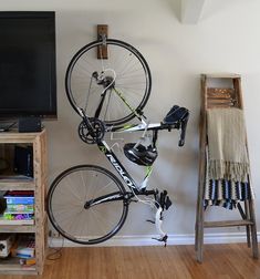 a bicycle mounted to the side of a wall next to a chair and television set