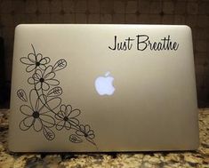 an apple laptop with the words just breathe on it's back and flowers painted on its side