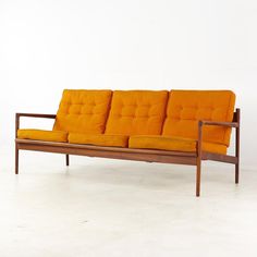 an orange couch sitting on top of a white floor next to a wooden framed wall