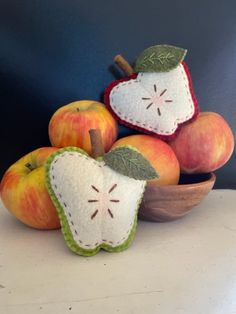 three apples and two pieces of fruit in a bowl