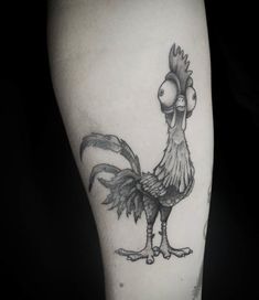 a black and white photo of a rooster tattoo on the right leg, with an eyeball in it's beak