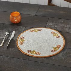 an orange vase sitting on top of a wooden table next to a plate and utensils