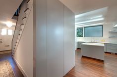 the stairs in this modern house are made of wood and white painted walls, along with hardwood flooring