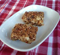 two pieces of granola on a white plate with red and white checkered tablecloth