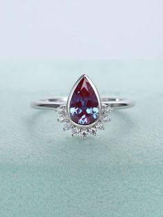 a white gold ring with a pear shaped blue topazte surrounded by small diamonds