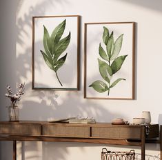 two green leaves are hanging on the wall next to a table with baskets and vases