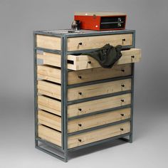 a wooden box with several drawers and a red suitcase on it's top, in front of a gray background