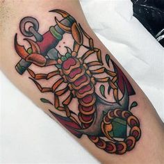 a colorful scorpion tattoo with an anchor on the side of his arm and some other items around it