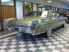 an antique car is parked in a showroom with checkered floor and black and white tile