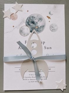 a white card with a blue ribbon tied around it and some stars on the side