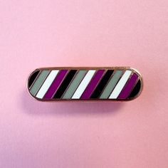 a purple and white striped pin sitting on top of a pink surface