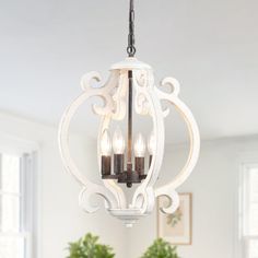 a chandelier hanging from the ceiling in a dining room with potted plants