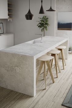 a kitchen with three stools and a long counter top in the middle of it