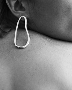 black and white photograph of a woman's back with earrings on her neck, close up