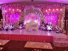 a stage set up for a wedding with pink and white flowers on the sidelines