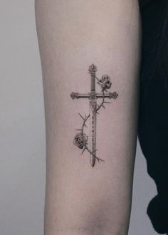 a cross tattoo on the arm with roses and a rosebud in between it