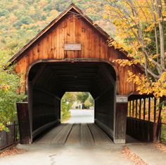 a wooden covered bridge over a river in the fall