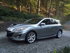 a silver car parked on top of a gravel road