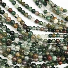 green and white marble beads are arranged in rows on a white surface, with one bead