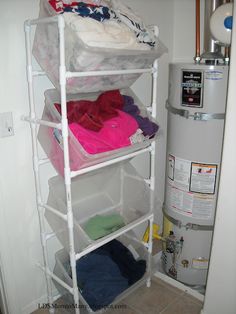 a white shelf filled with clothes next to a water heater