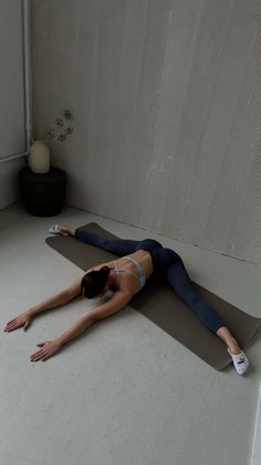 a woman is laying on her stomach on a yoga mat