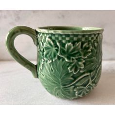 a green coffee cup sitting on top of a white countertop next to a wall