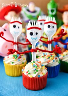 cupcakes decorated with cartoon faces and sprinkles are on a table