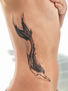 a woman's back with a black and white tattoo design on her lower body