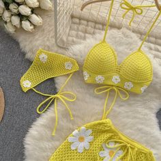 two yellow bikinisuits with white flowers on them and a straw hat next to it