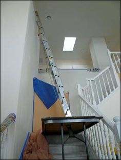 a ladder that is next to a table on the stairs in a room with white railings