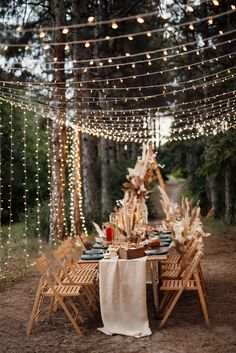 an outdoor dinner table set up with string lights