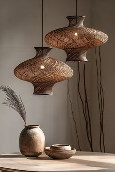 three lamps hanging from the ceiling above a table with vases and bowls on it