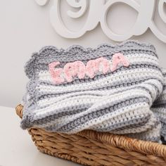 a basket filled with blankets sitting on top of a white shelf next to a wall