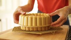 a woman is decorating a cake on a wooden table