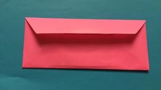 an empty pink envelope sitting on top of a green surface with the bottom half cut off