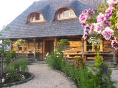 a wooden house with flowers in the front yard