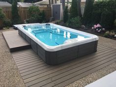 a large hot tub sitting on top of a wooden deck next to a garden area