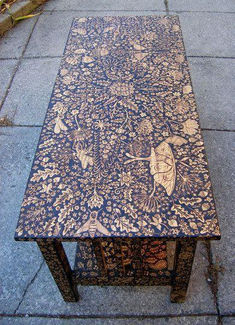 a table that is sitting on the sidewalk with an insect design on it's surface