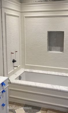 a bathroom with white walls and tile flooring, including a bathtub in the middle